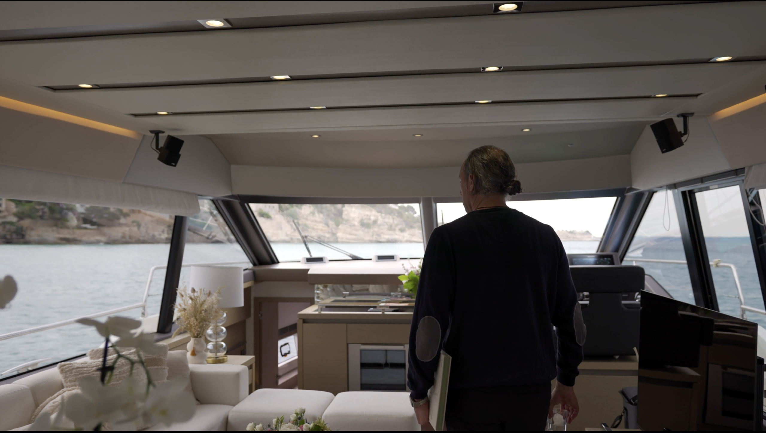 Person at the helm of a yacht overlooking a calm bay