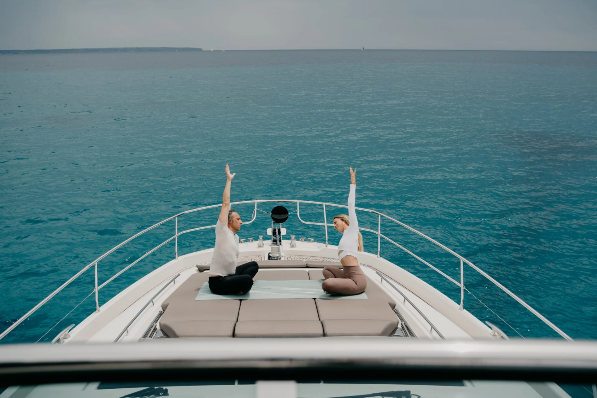 Two people stretching on the bow of a yacht