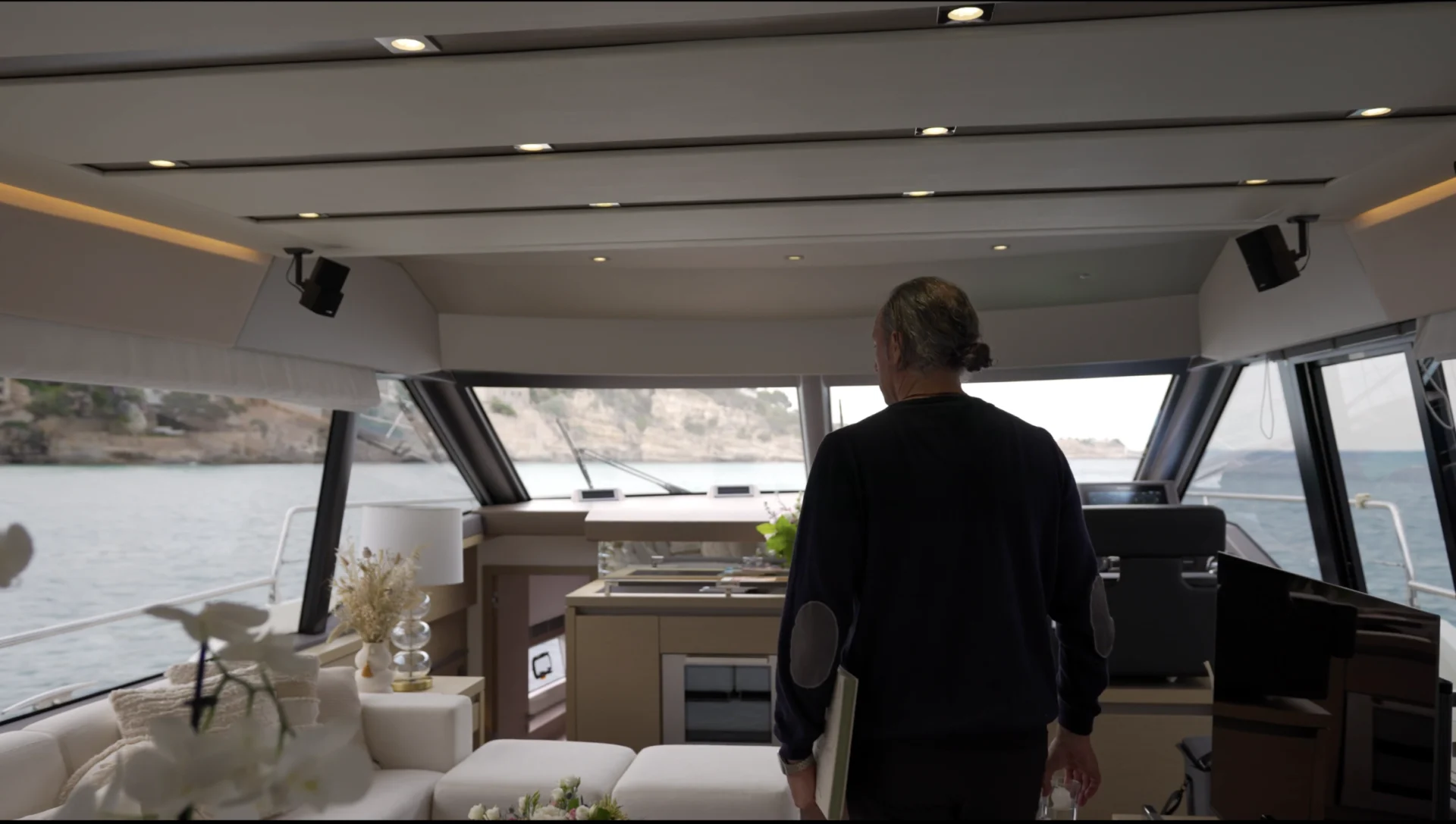 Person at the helm of a yacht overlooking a calm bay
