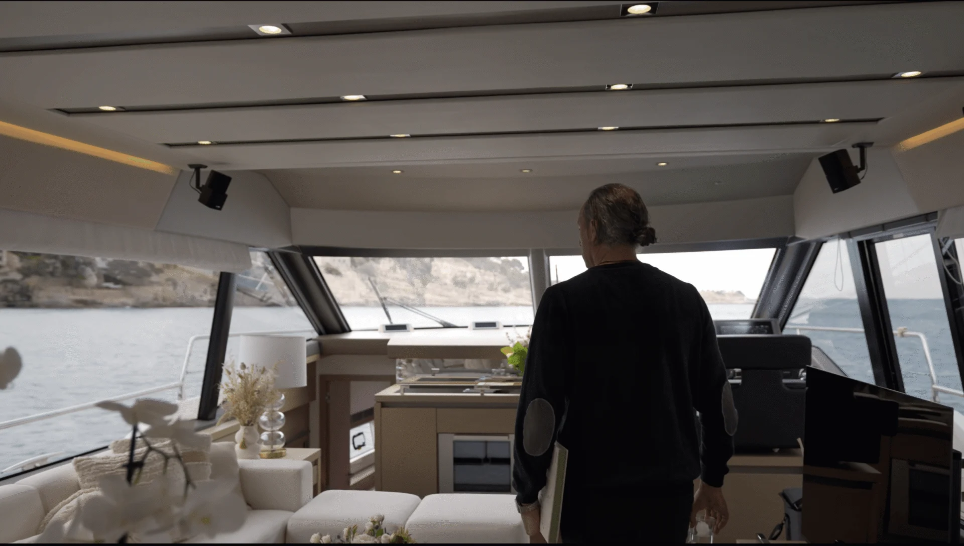 Person am Steuer einer Yacht mit Blick auf eine ruhige Bucht